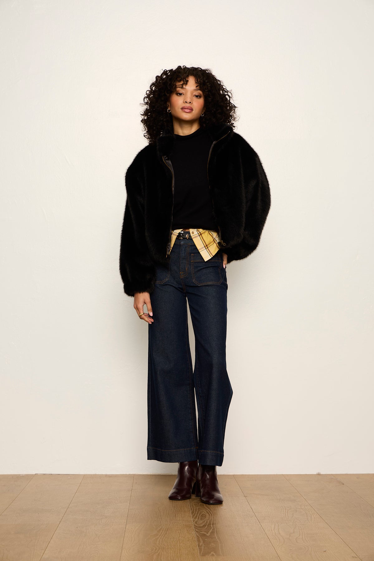 Person wearing a black outfit with wide-leg jeans and a black jacket against a white background