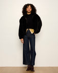 Person wearing a black outfit with wide-leg jeans and a black jacket against a white background