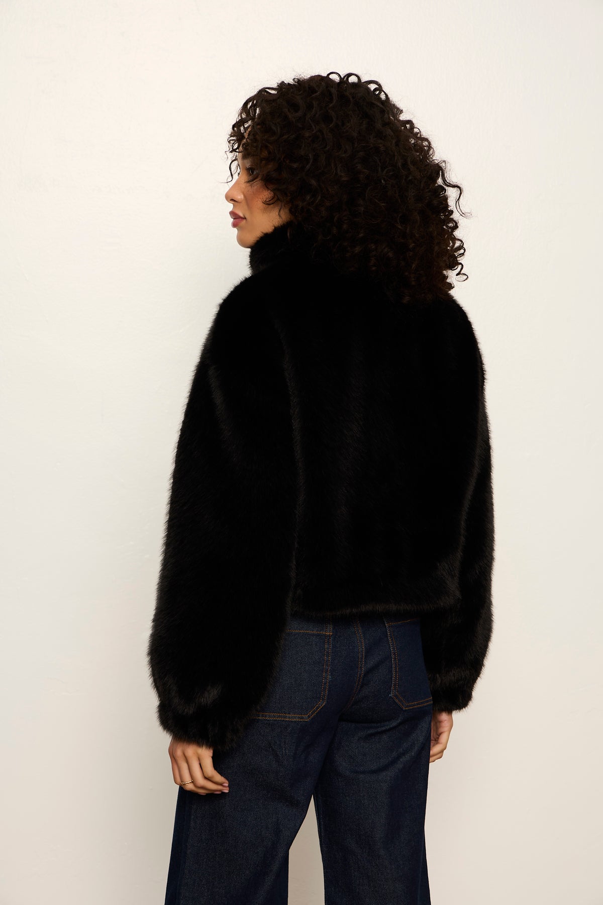 Person wearing a black fluffy sweater against a white background