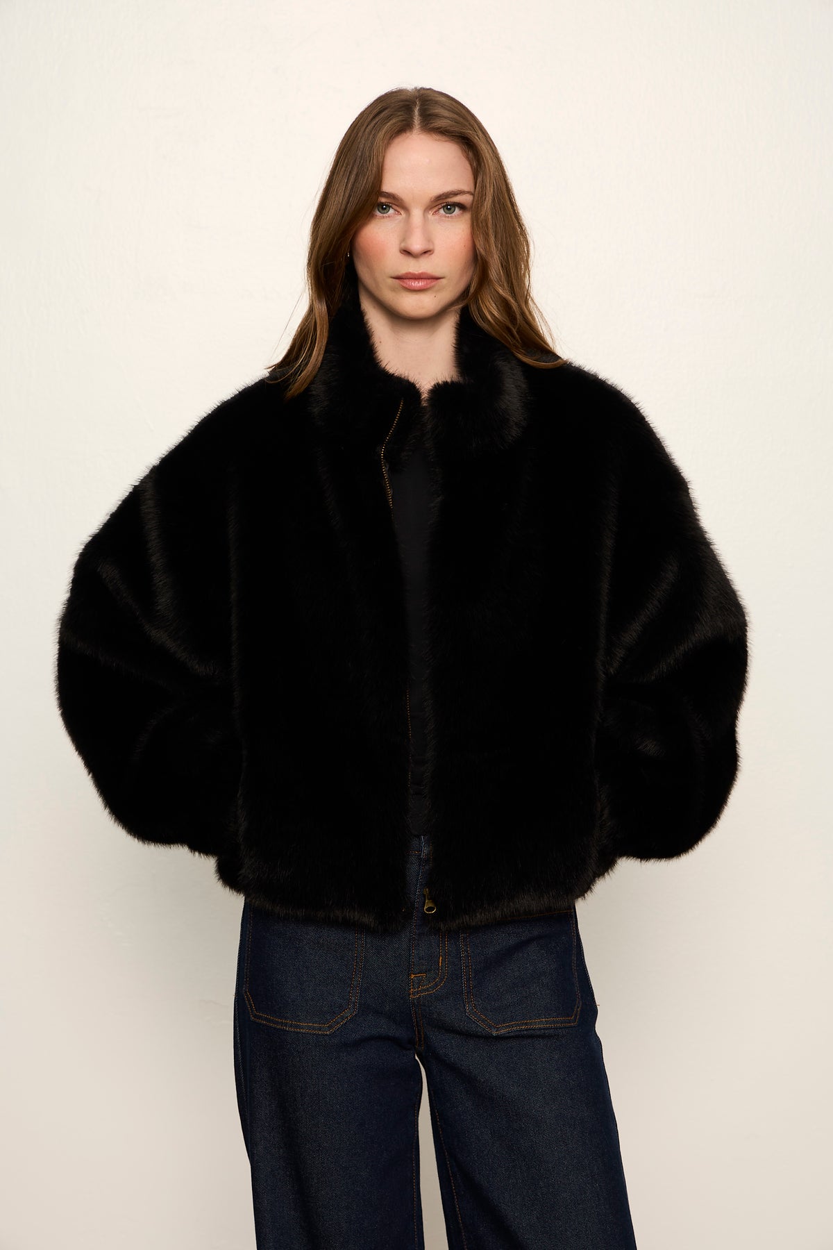 Person wearing a black fur coat against a white background