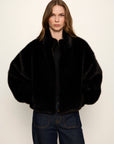 Person wearing a black fur coat against a white background