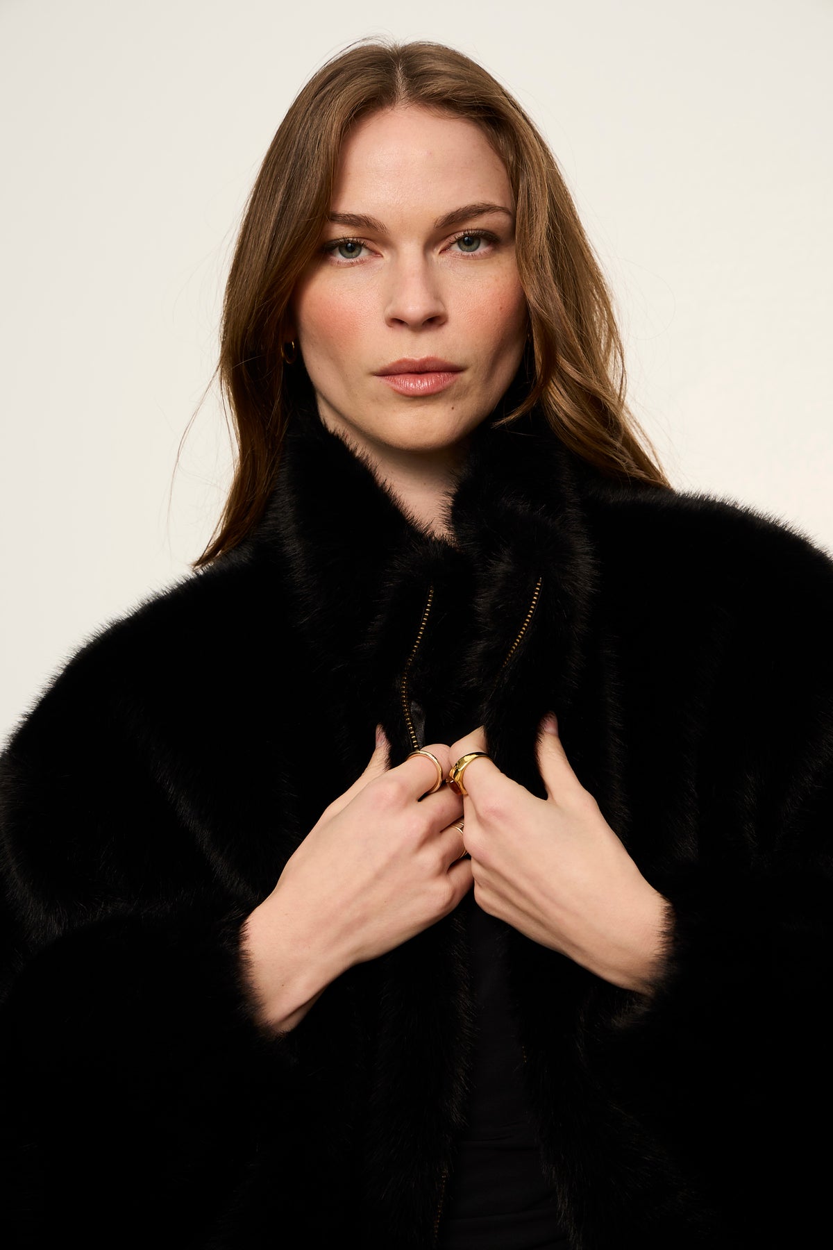Woman wearing a black fur coat against a plain background