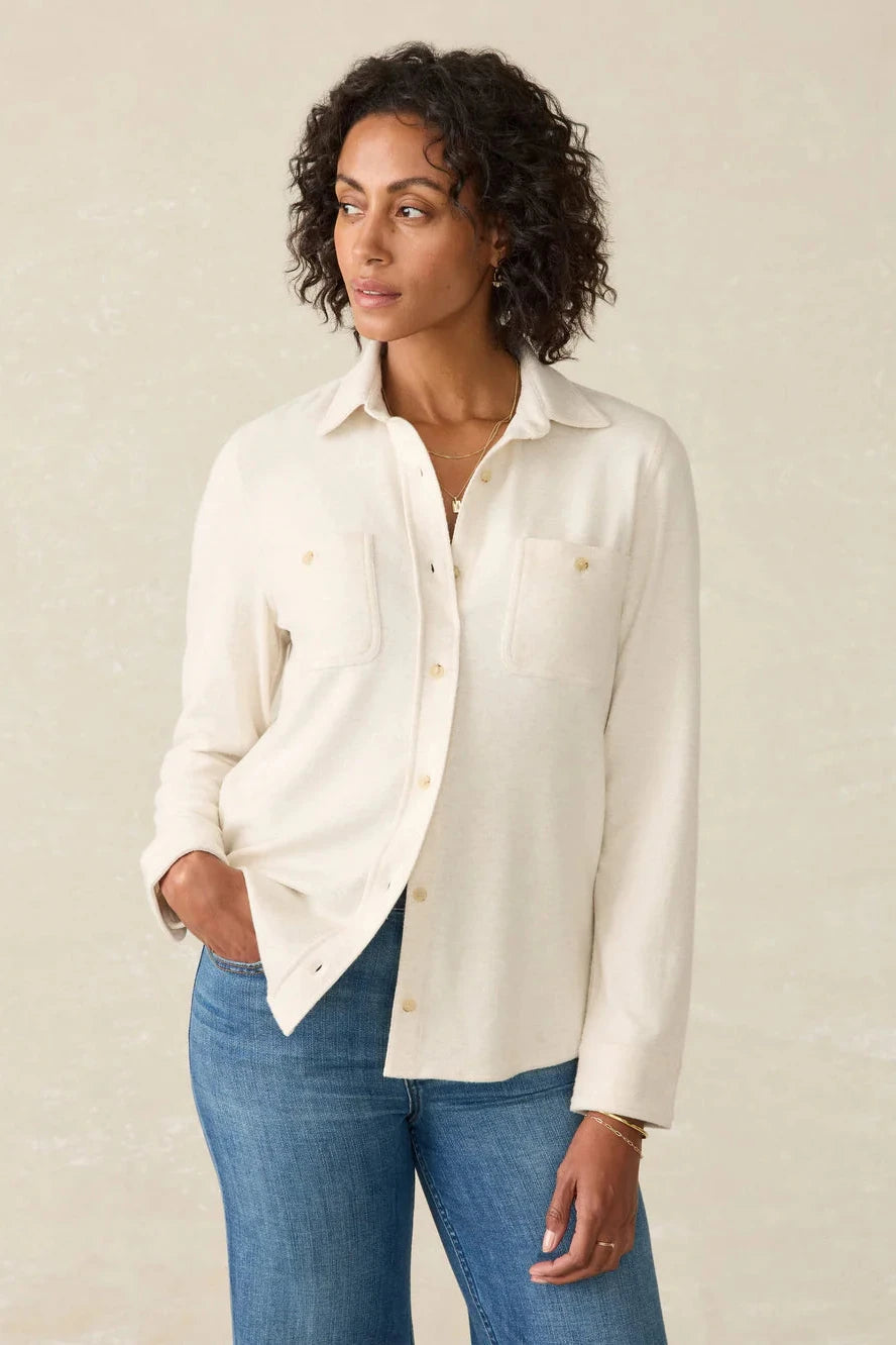 Woman wearing a white blouse and blue jeans against a beige background
