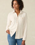 Woman wearing a white blouse and blue jeans against a beige background