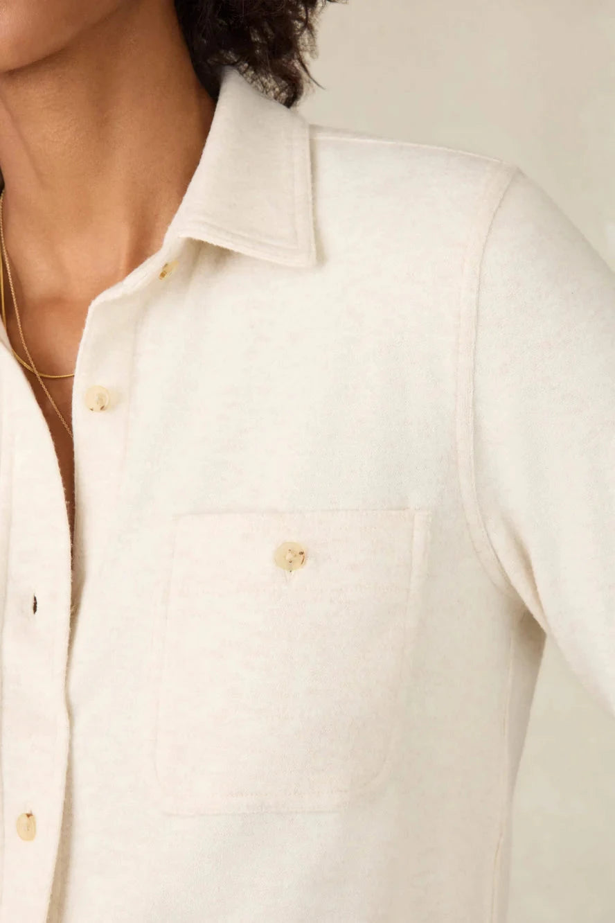 Close-up of a person wearing a light-colored shirt with a neutral background