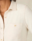 Close-up of a person wearing a light-colored shirt with a neutral background