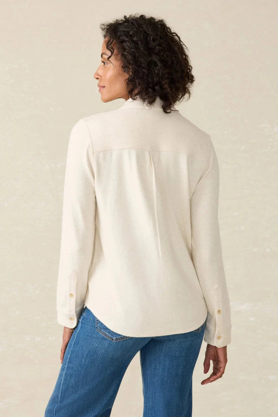 Woman wearing a cream blouse and blue jeans against a beige background