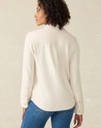 Woman wearing a cream blouse and blue jeans against a beige background