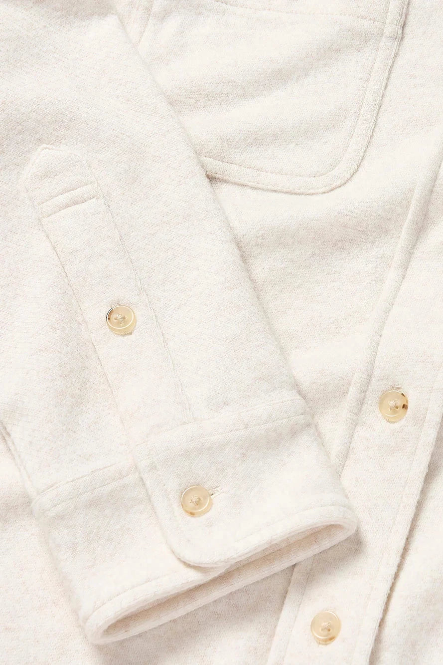 Close-up of a white shirt with gold buttons on a light background