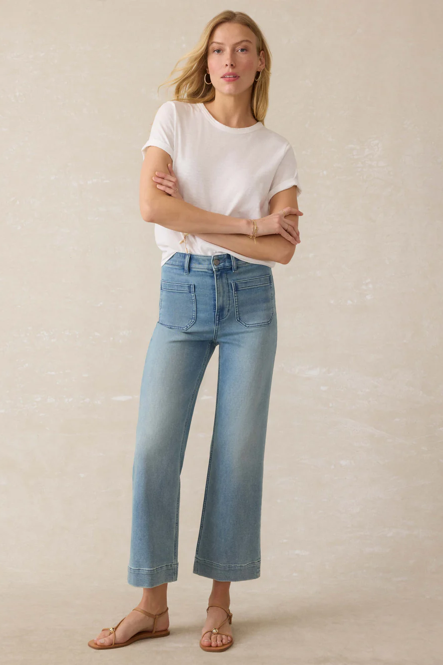 Woman wearing a white t-shirt and light blue jeans against a beige background