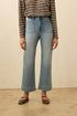 Person wearing a striped shirt and light blue jeans against a beige background