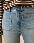 Close-up of blue jeans with a striped shirt worn underneath.