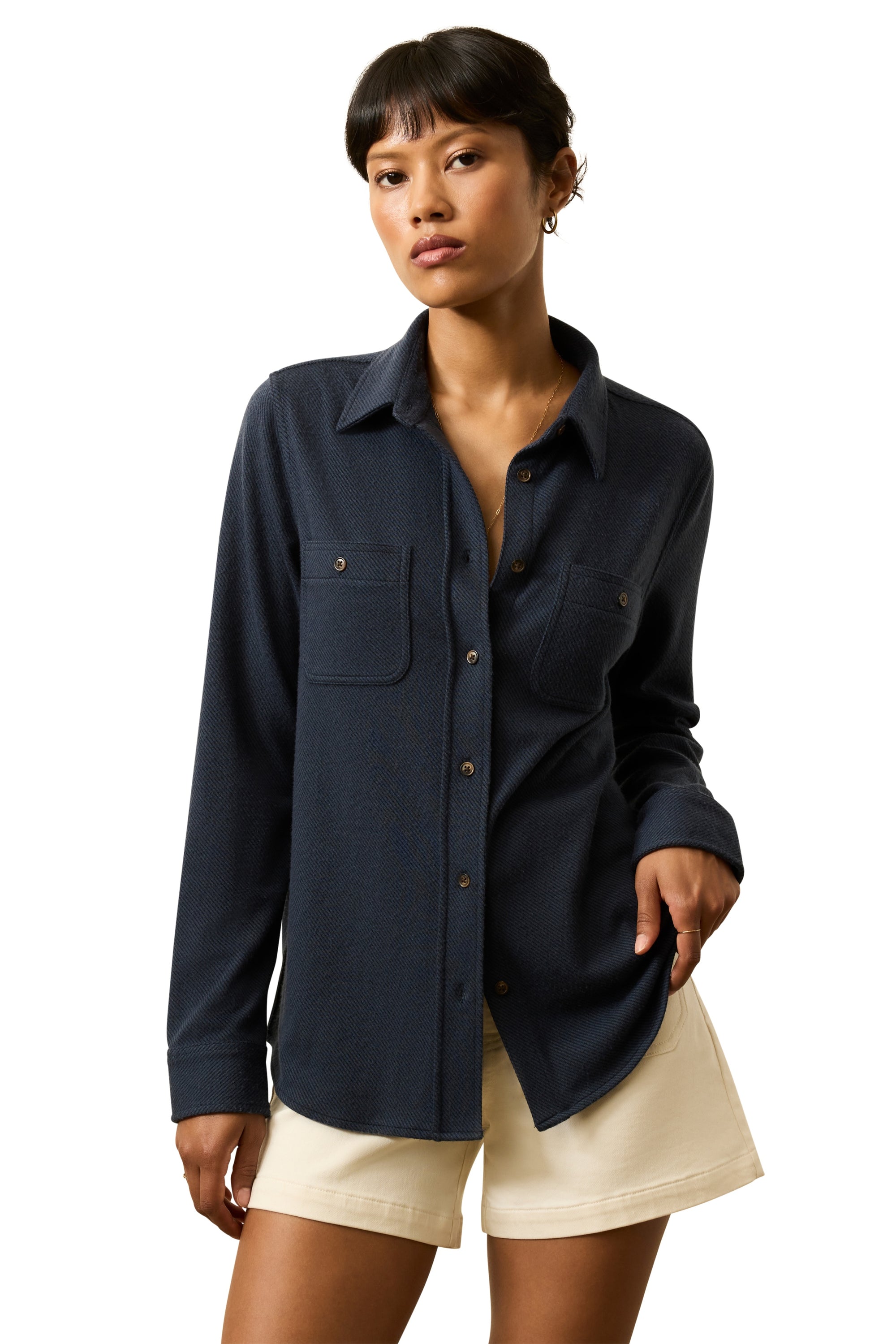 Woman wearing a navy blue shirt and beige shorts on a white background
