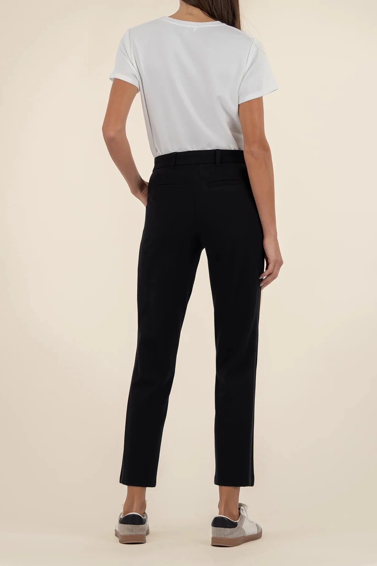 Person wearing black pants and a light gray shirt on a beige background