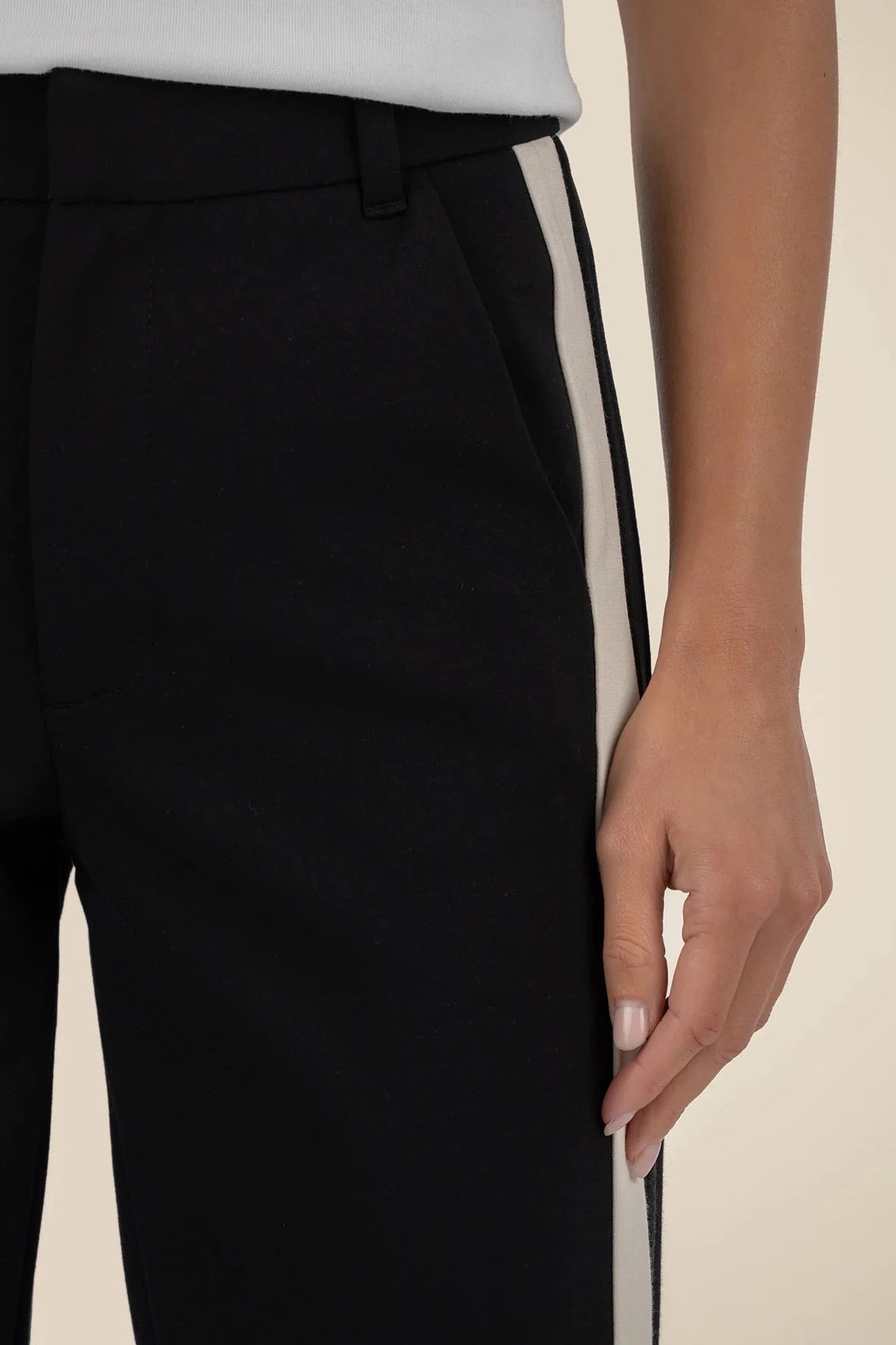 Black pants with a white stripe on a beige background