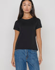 Woman wearing a black t-shirt and blue jeans against a plain background