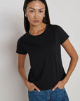 Woman wearing a black t-shirt and blue jeans against a plain background