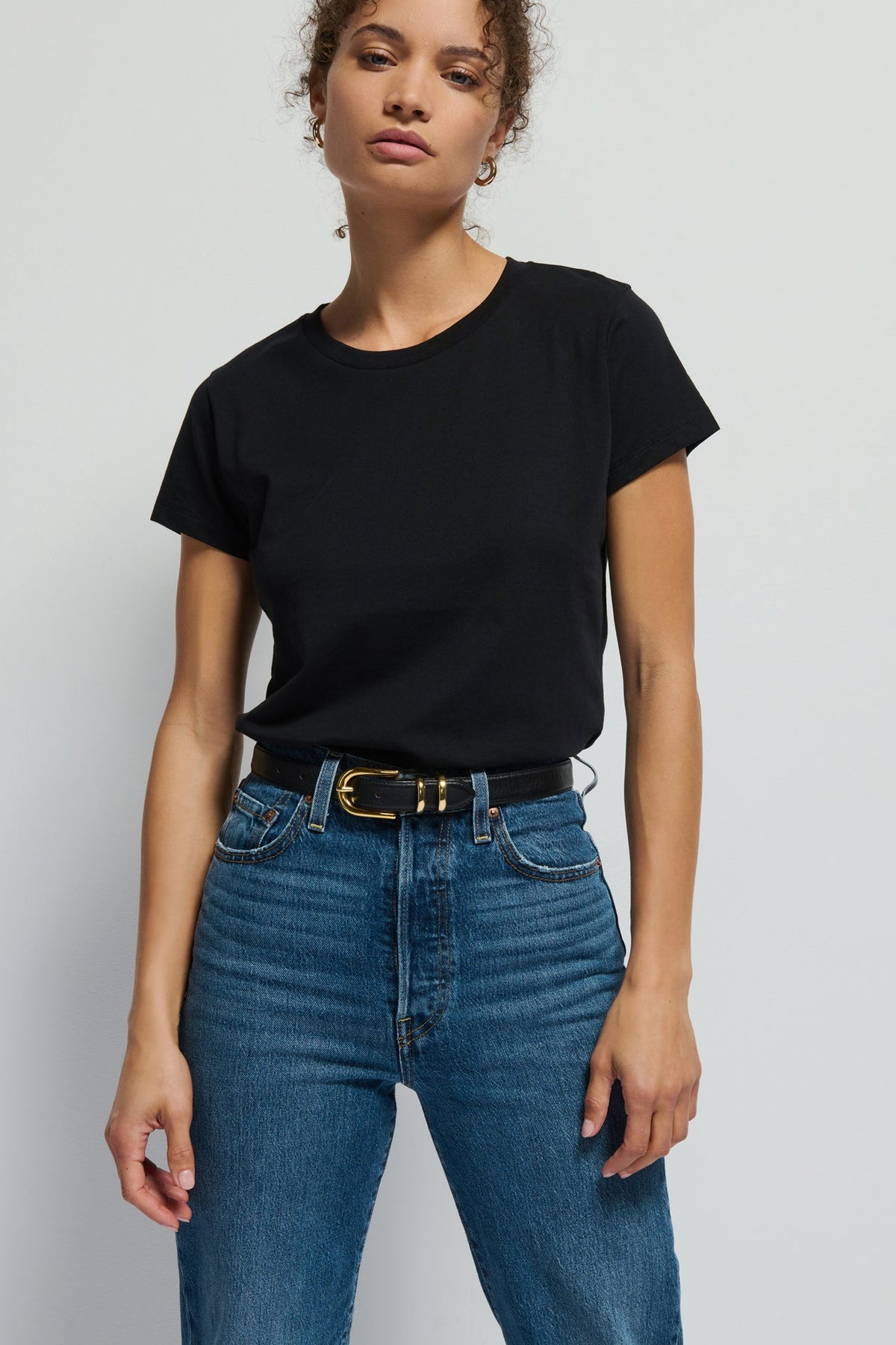 Person wearing a black t-shirt and blue jeans against a plain background