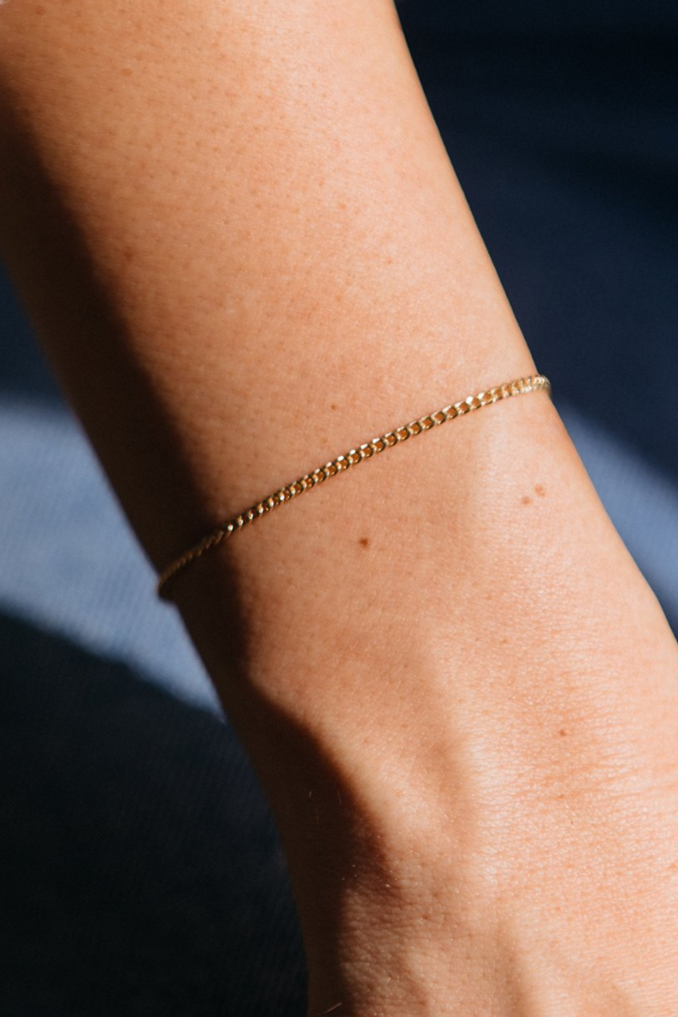 Gold bracelet on a wrist with a blurred background