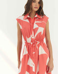 Woman wearing a sleeveless dress with a red and white floral pattern on a white background