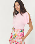 Woman wearing a pink top and floral skirt on a white background