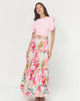 Woman wearing a pink top and floral skirt on a white background