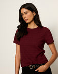 Woman wearing a maroon t-shirt against a plain background