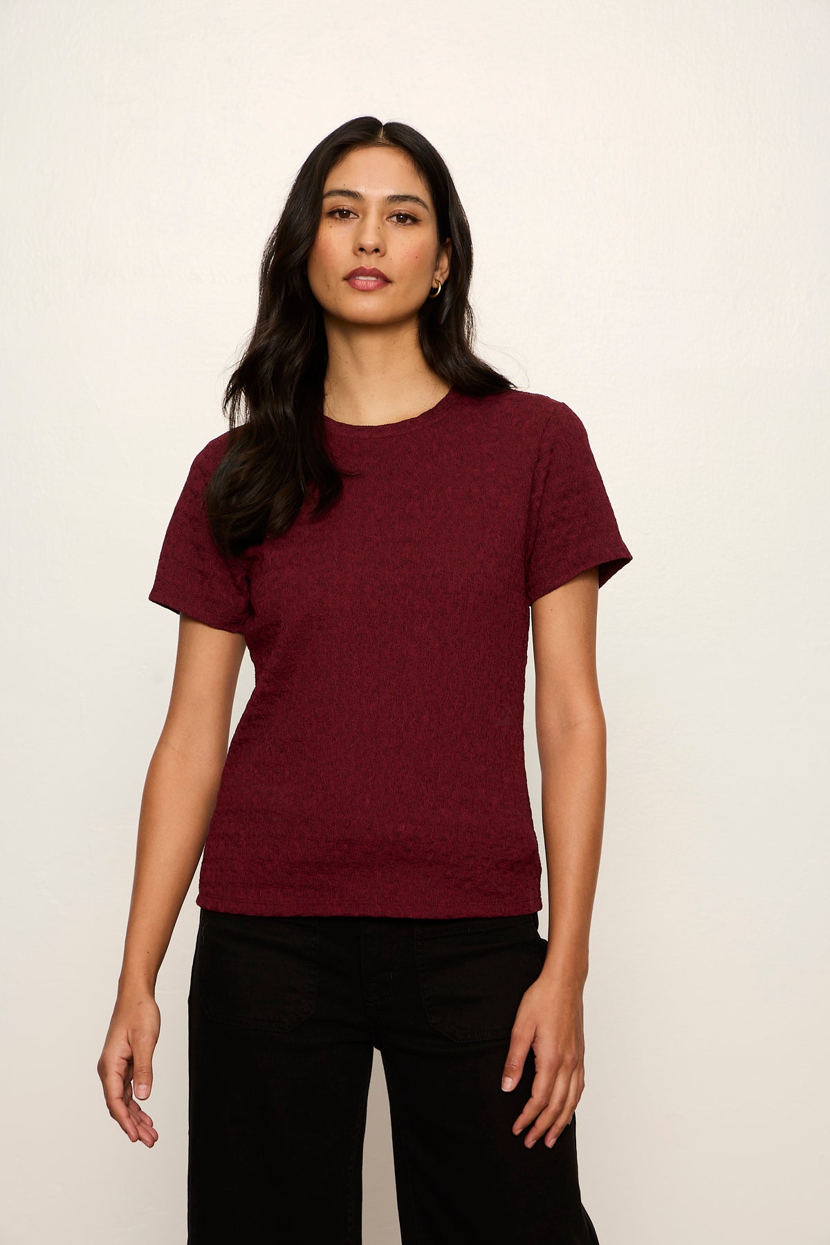 Woman wearing a maroon t-shirt against a plain background