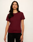 Woman wearing a maroon t-shirt against a plain background