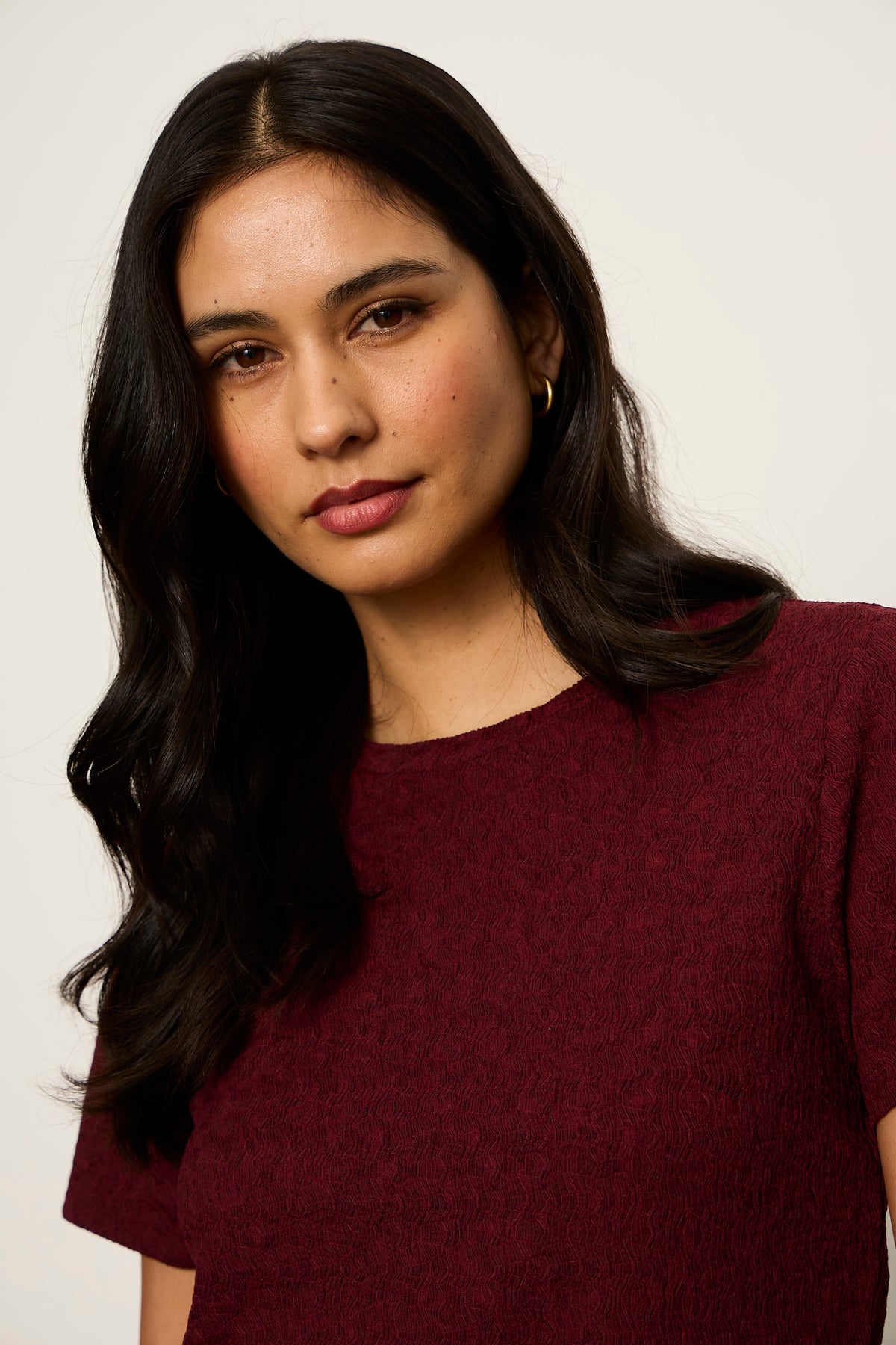 Woman wearing a burgundy shirt against a plain background