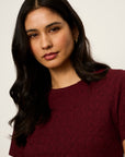 Woman wearing a burgundy shirt against a plain background