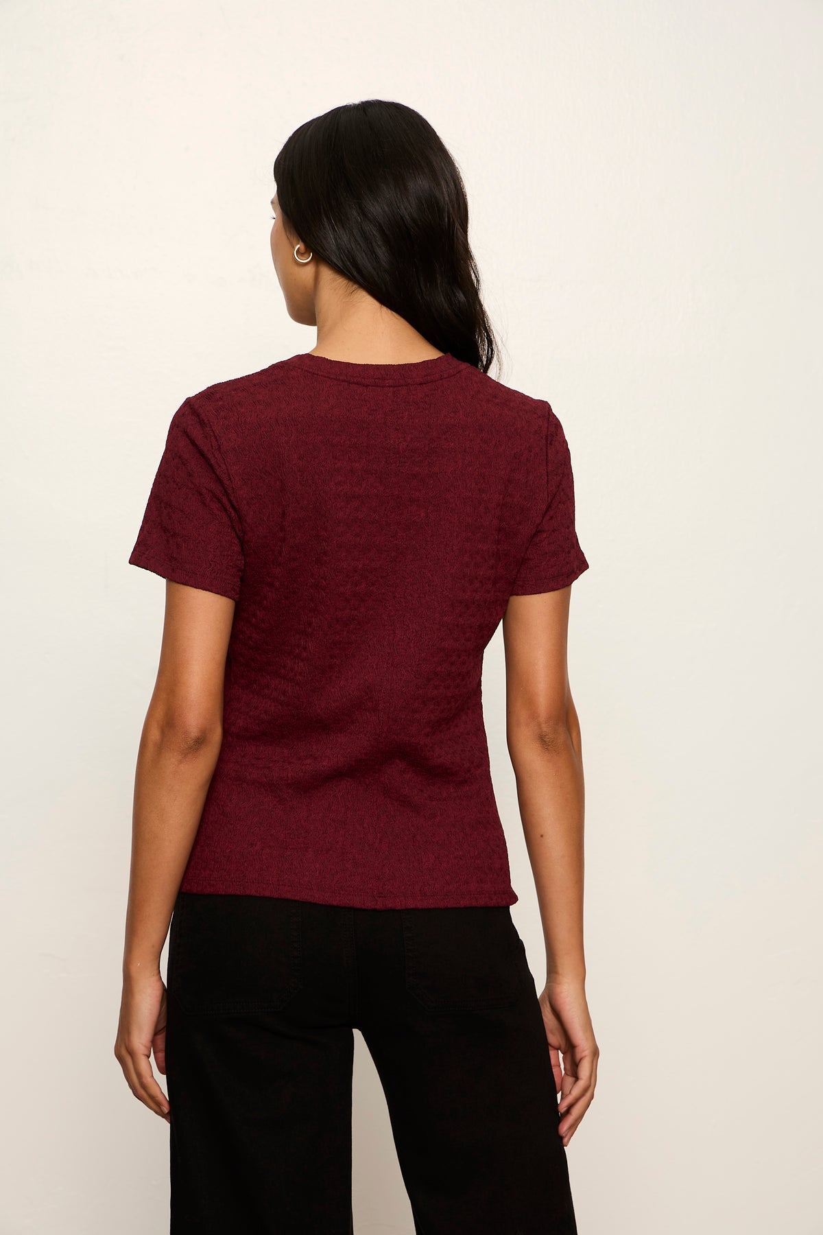 Person wearing a maroon t-shirt on a plain background