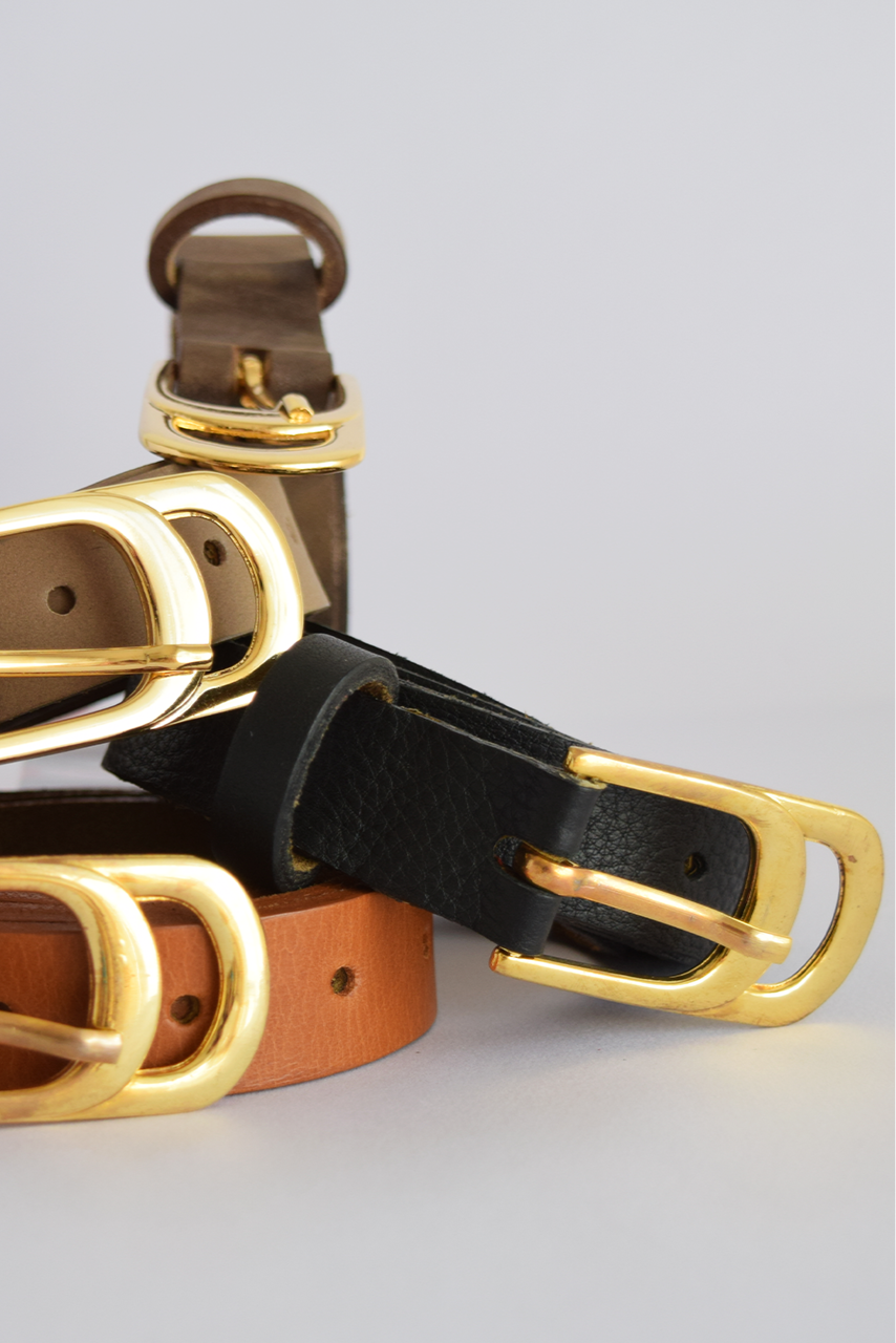 Three leather belts with gold buckles on a light gray background