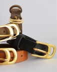 Three leather belts with gold buckles on a light gray background