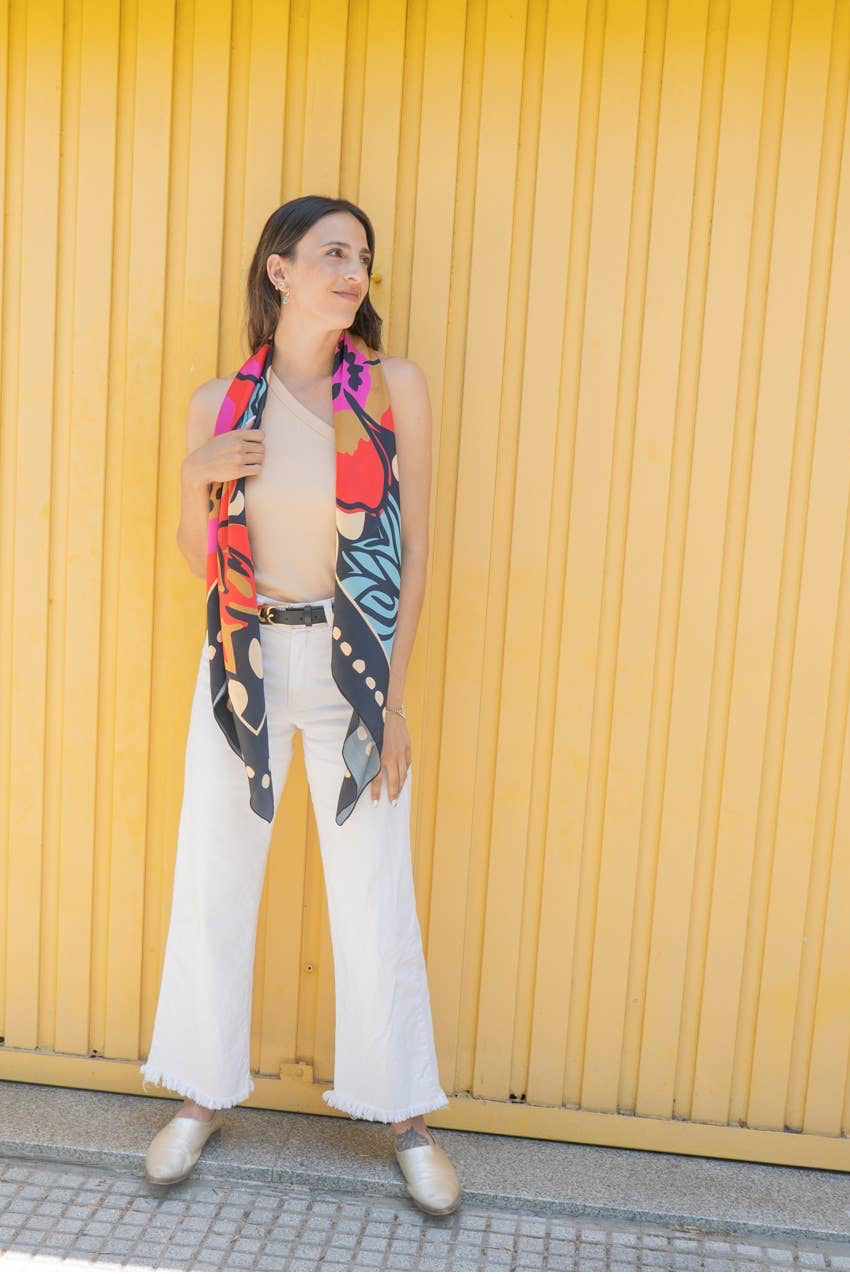 Woman wearing a colorful butterfly-patterned scarf against a yellow wall.