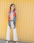 Woman wearing a colorful butterfly-patterned scarf against a yellow wall.