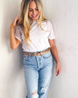 Woman wearing a white t-shirt and light blue jeans against a plain background