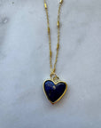 Heart-shaped lapis lazuli pendant on a gold chain against a marble background