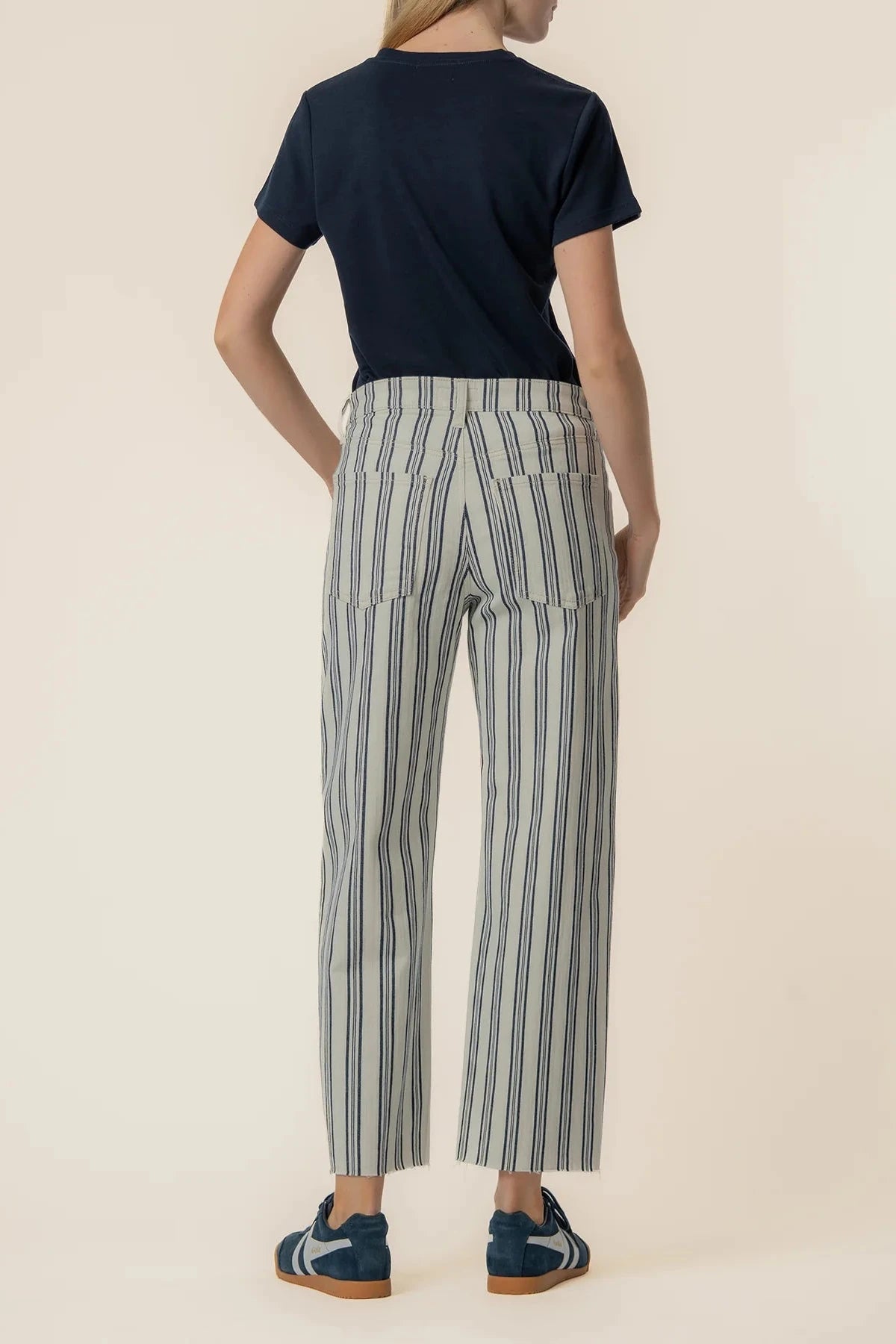 Person wearing a navy shirt and striped pants on a beige background