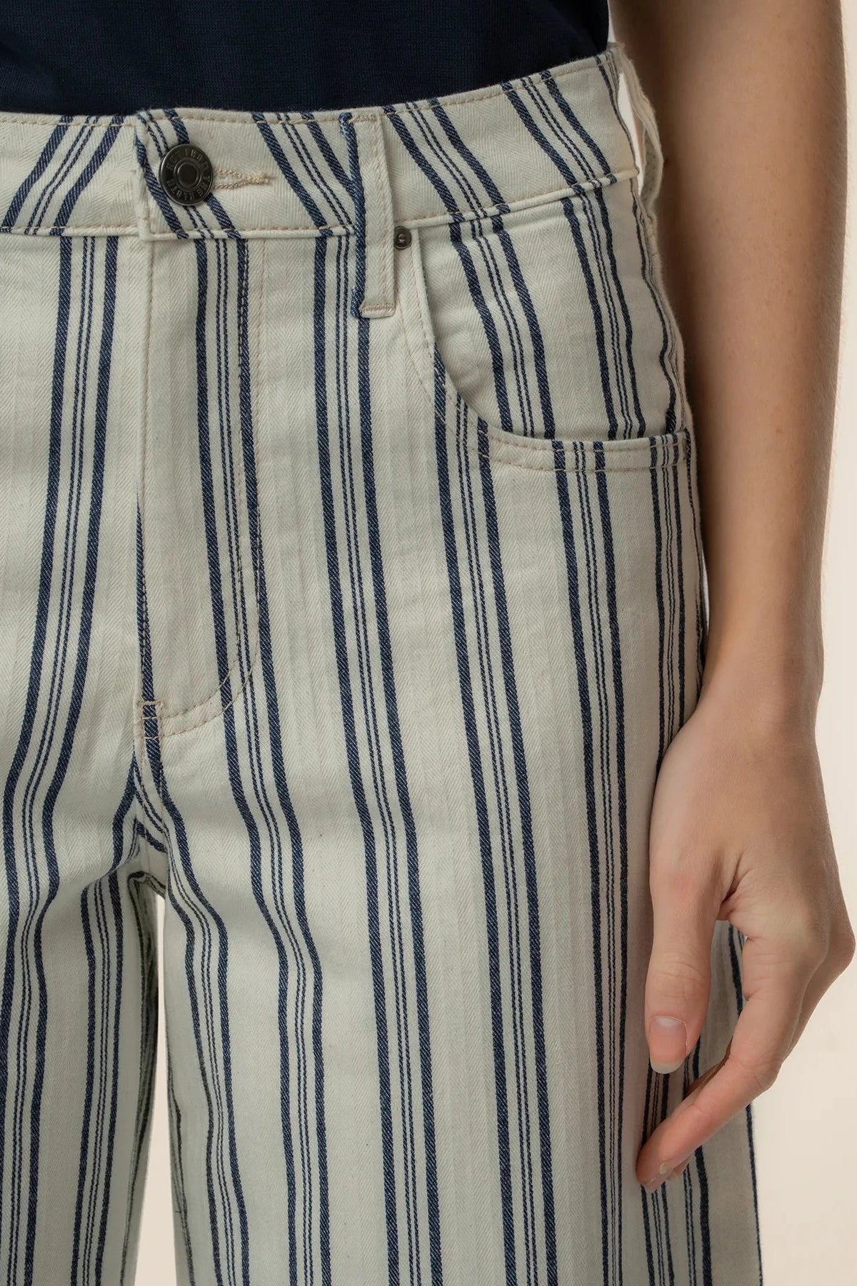 Close-up of a person wearing striped pants with a neutral background
