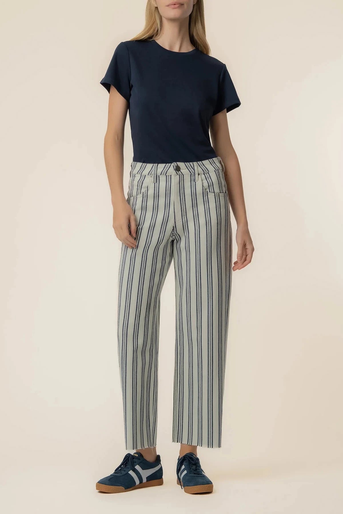 Person wearing a navy t-shirt and striped pants on a beige background