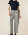 Person wearing a navy t-shirt and striped pants on a beige background