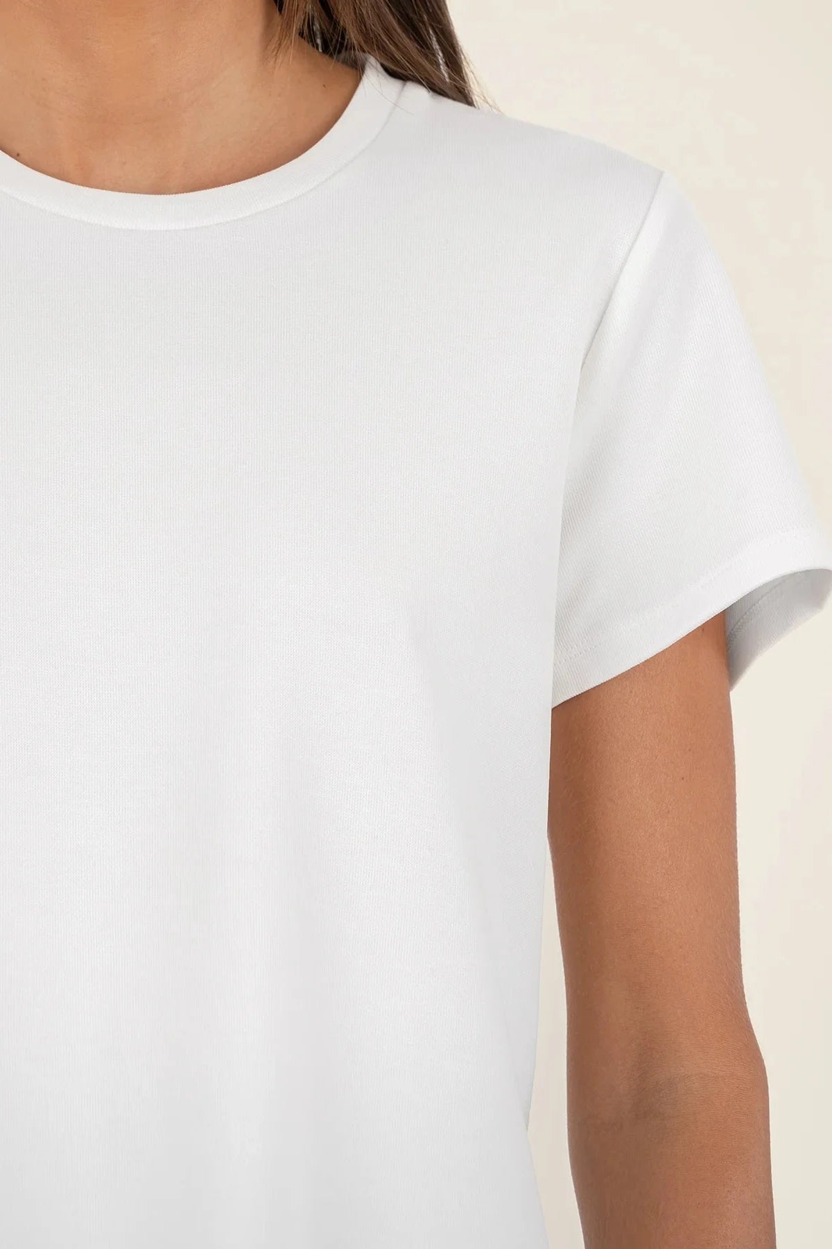 White sleeveless top worn by a person on a beige background