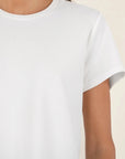 White sleeveless top worn by a person on a beige background
