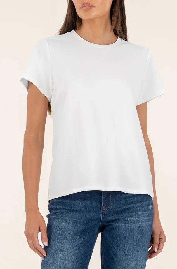 Person wearing a plain white t-shirt and blue jeans on a beige background