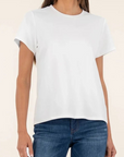 Person wearing a plain white t-shirt and blue jeans on a beige background
