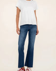 Person wearing a white t-shirt and blue jeans with red sneakers on a beige background