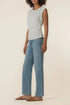 Woman wearing a light blue sleeveless top and jeans on a beige background