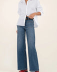 Person wearing a white shirt, blue jeans, and red shoes on a beige background