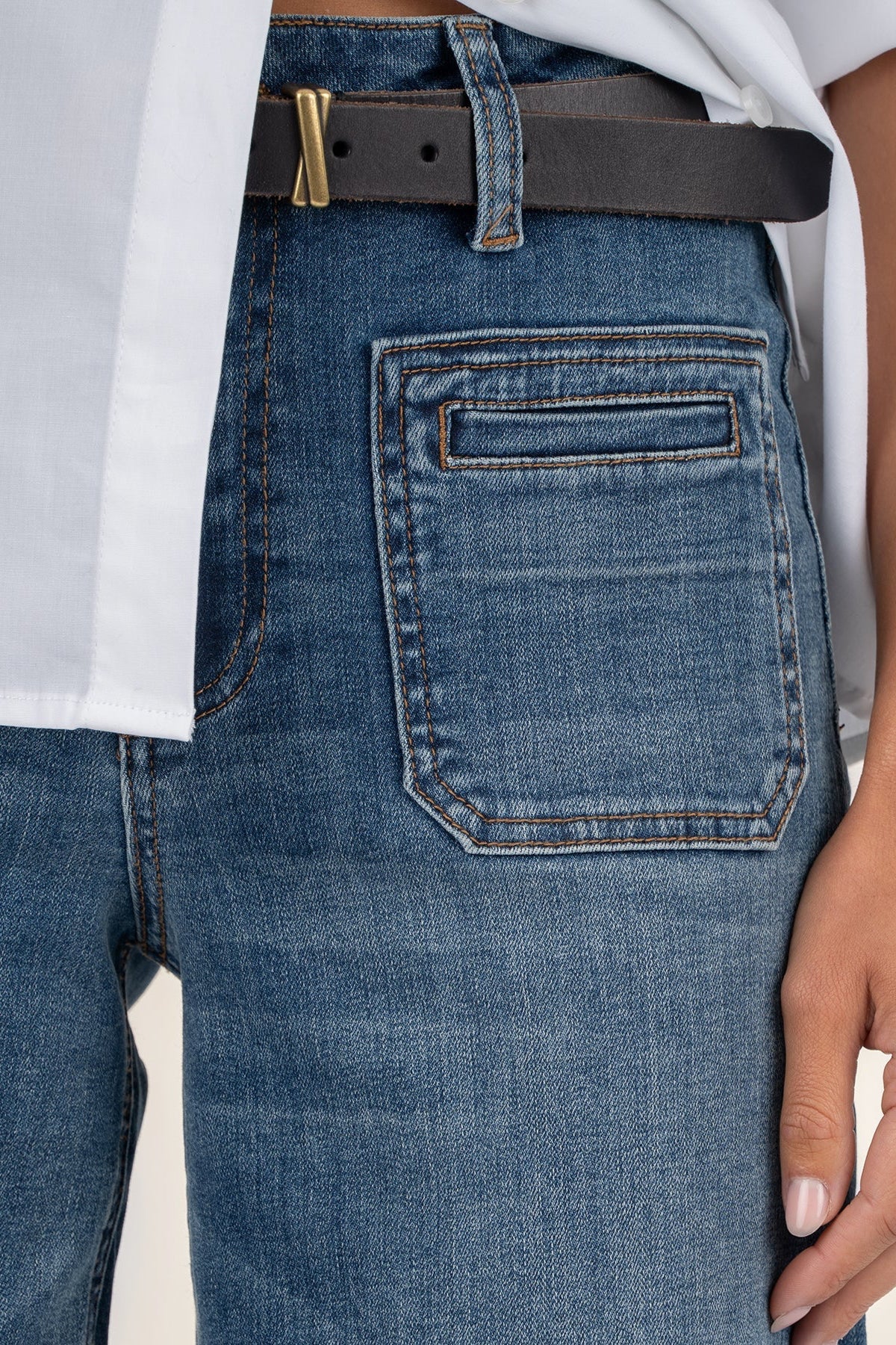 Close-up of blue jeans with a white shirt and black belt.